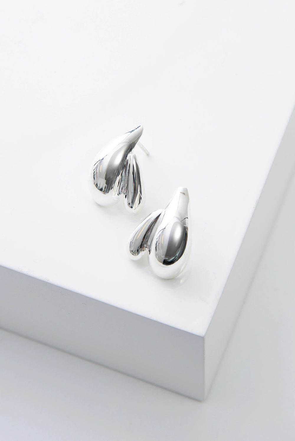 Pair of silver earrings on a white surface
