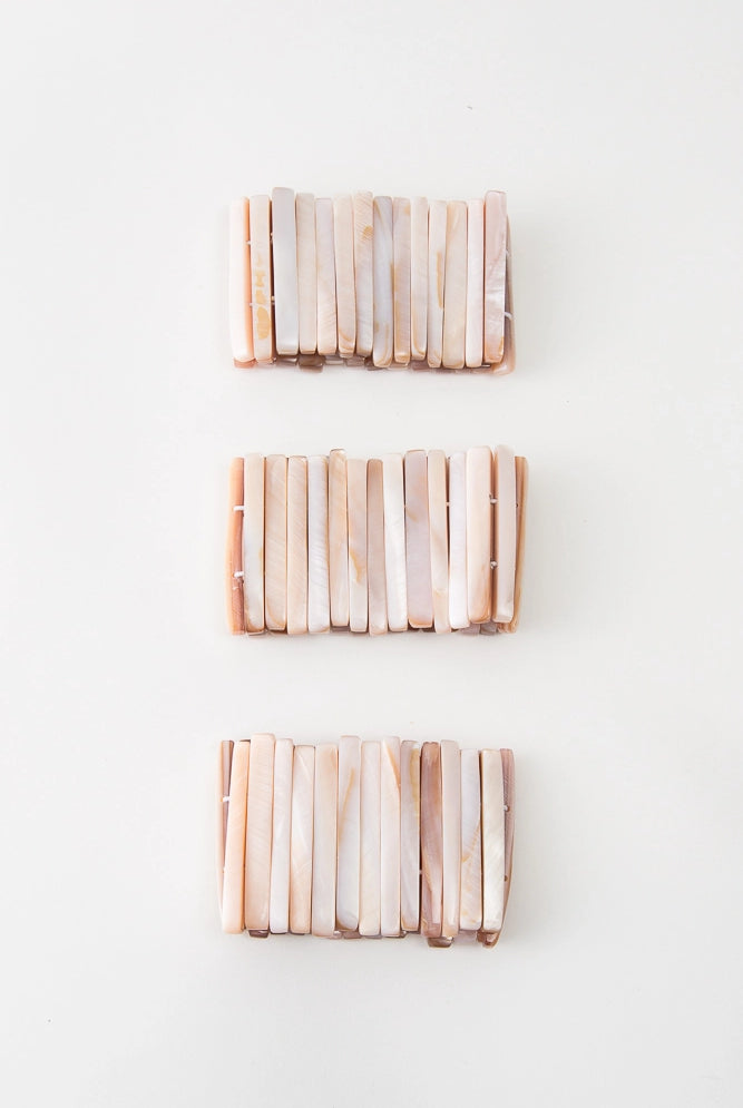 Three Beachcomber Bracelets are pictured. Due to the natural shell used, each varies slightly in shade. However, all have peach and white tones.