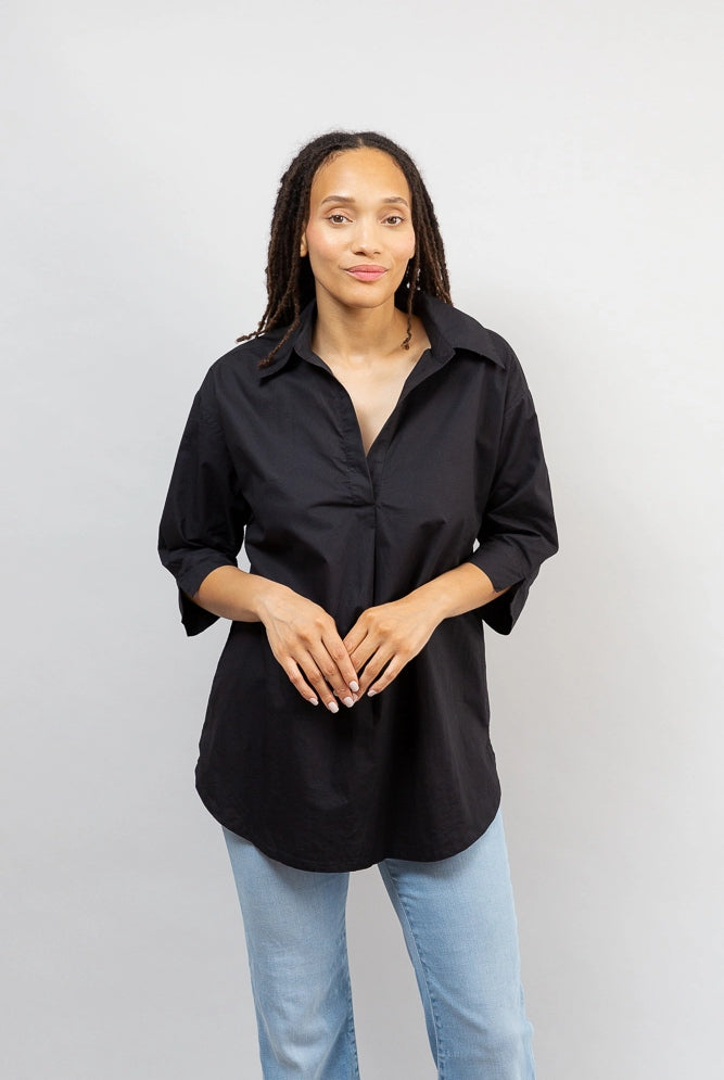 A model wears the Black Breezy Tunic untucked. It hits a few inches below her hips.