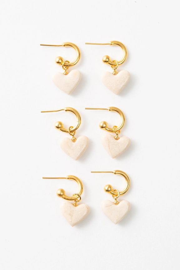 Three pairs of Convertible Heart Huggies are pictured, showing the natural variations in each marble heart charm. Each is cream colored, but the marble markings vary slightly.