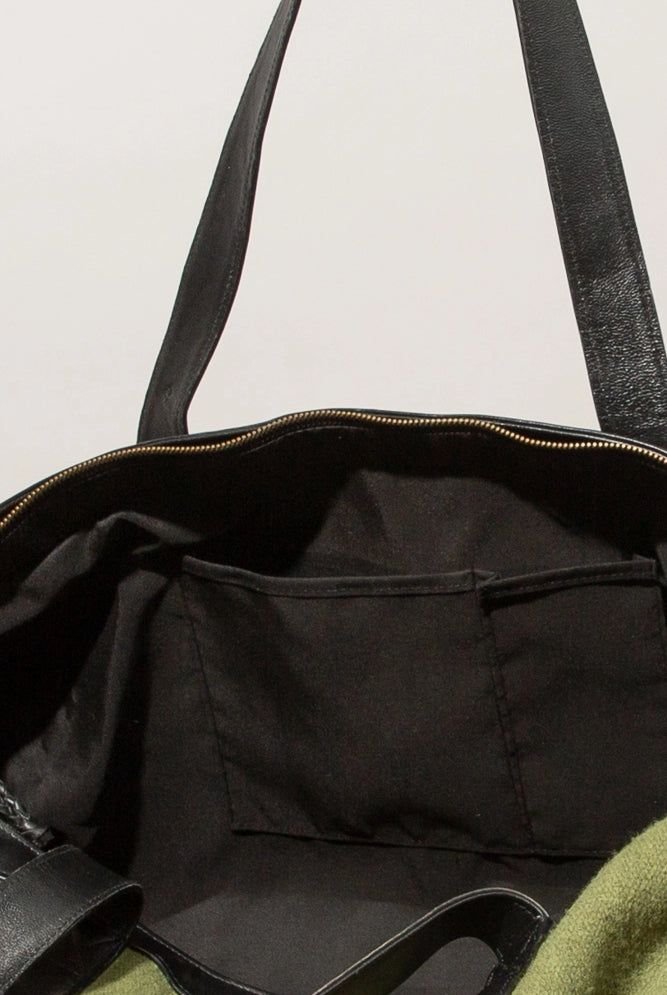 The interior of the bag is pictured. The bag has a black fabric lining and two fabric slot pockets stitched into the front wall of the bag.
