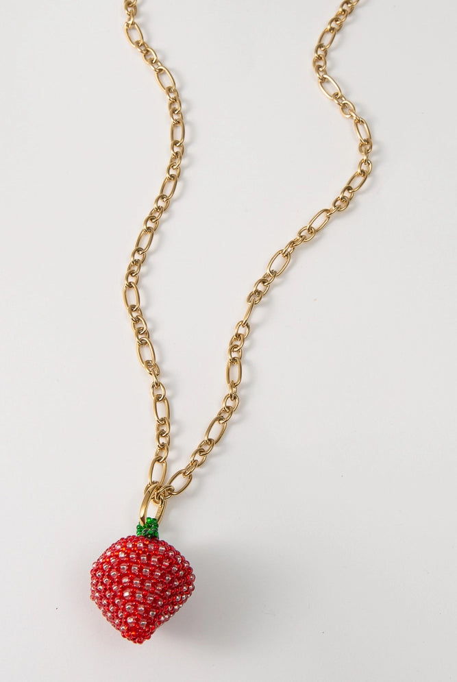 The Fresca Necklace has a gold chain with elongated links that vary in size. At the base of the necklace is a three-dimensional strawberry pendant composed entirely of translucent glass beads.