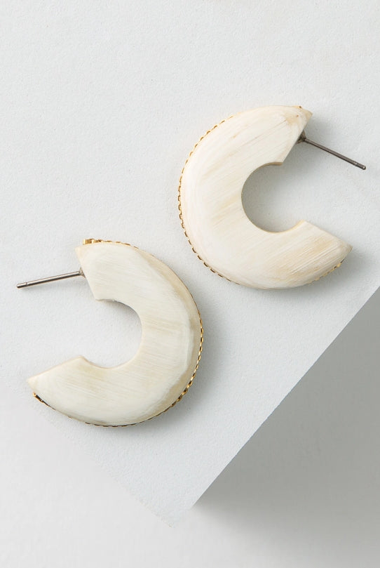 The Fusion Hoops are midsize, flat hoops. They are open at the back. They are composed of white horn with a tiny gold chain running along the exterior of the hoop.