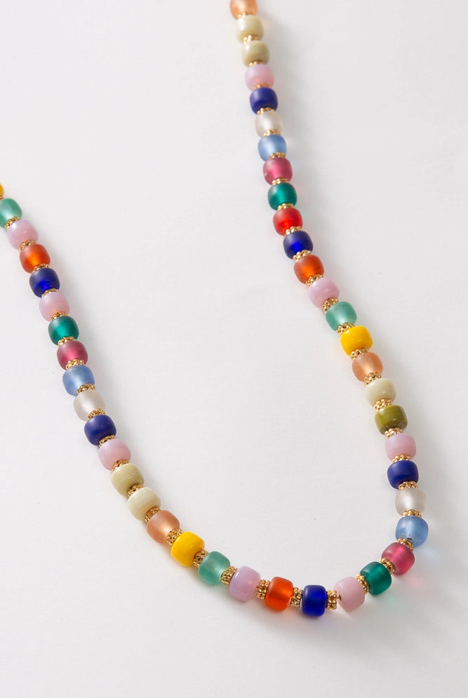 The Glass Confetti Necklace is a single stranded necklace composed of brightly colored glass beads. The bead colors span nearly every color of the rainbow. Between each glass bead there is a copper bead, giving the necklace some subtle glimmer.