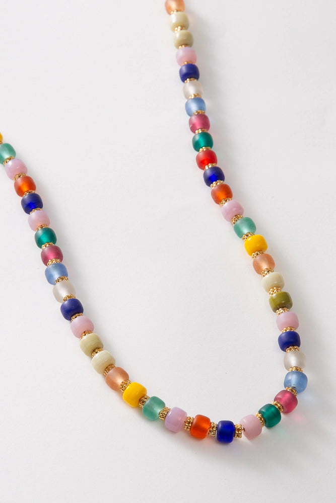 The Glass Confetti Necklace is a single stranded necklace composed of brightly colored glass beads. The bead colors span nearly every color of the rainbow. Between each glass bead there is a copper bead, giving the necklace some subtle glimmer.