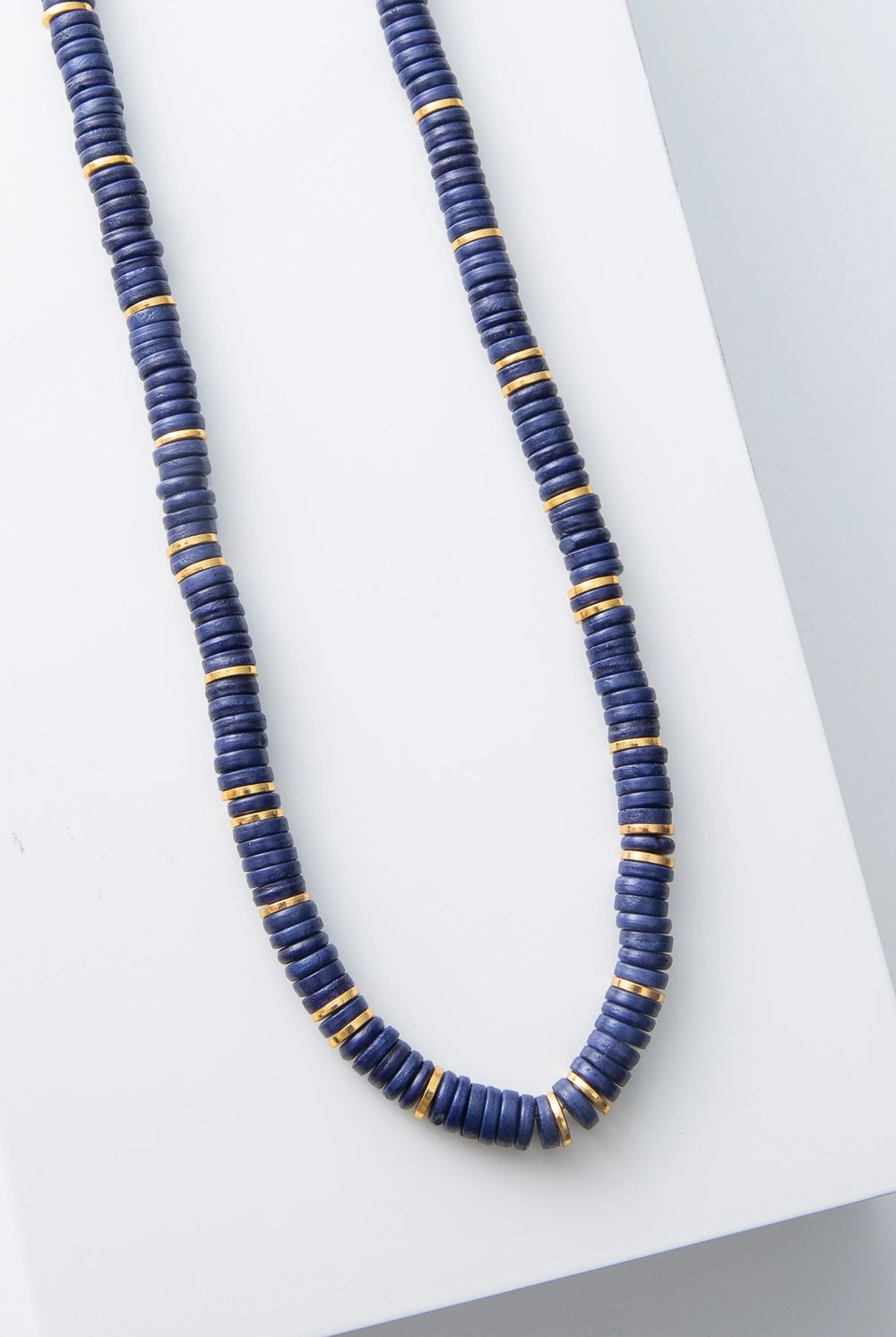 This is a single-strand necklace composed of hundreds of cobalt blue disc-shaped beads. Every inch or so, there are shining gold disc beads strung between the blue beads.