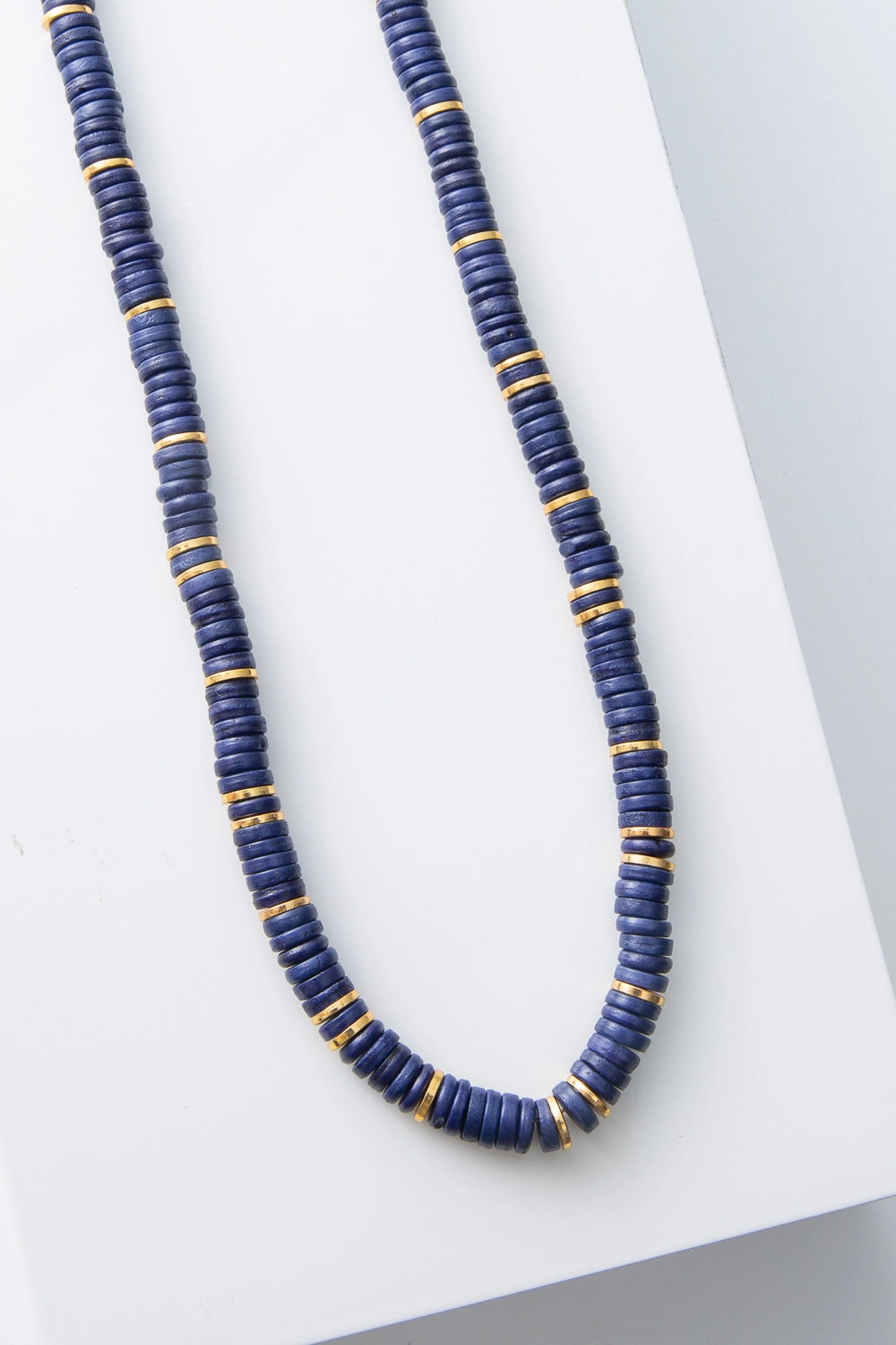 This is a single-strand necklace composed of hundreds of cobalt blue disc-shaped beads. Every inch or so, there are shining gold disc beads strung between the blue beads.