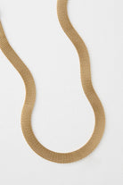 The Interwoven Necklace is a short, ribbon-style necklace composed entirely of gold plated metal links. The tiny links form a broad, flat chain.