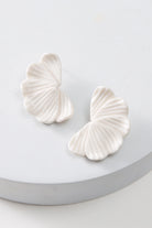 The Porcelain Petal Earrings are post-style earrings composed of white porcelain. The earrings feature several porcelain petals that overlap and fan out to create a half-moon shape.