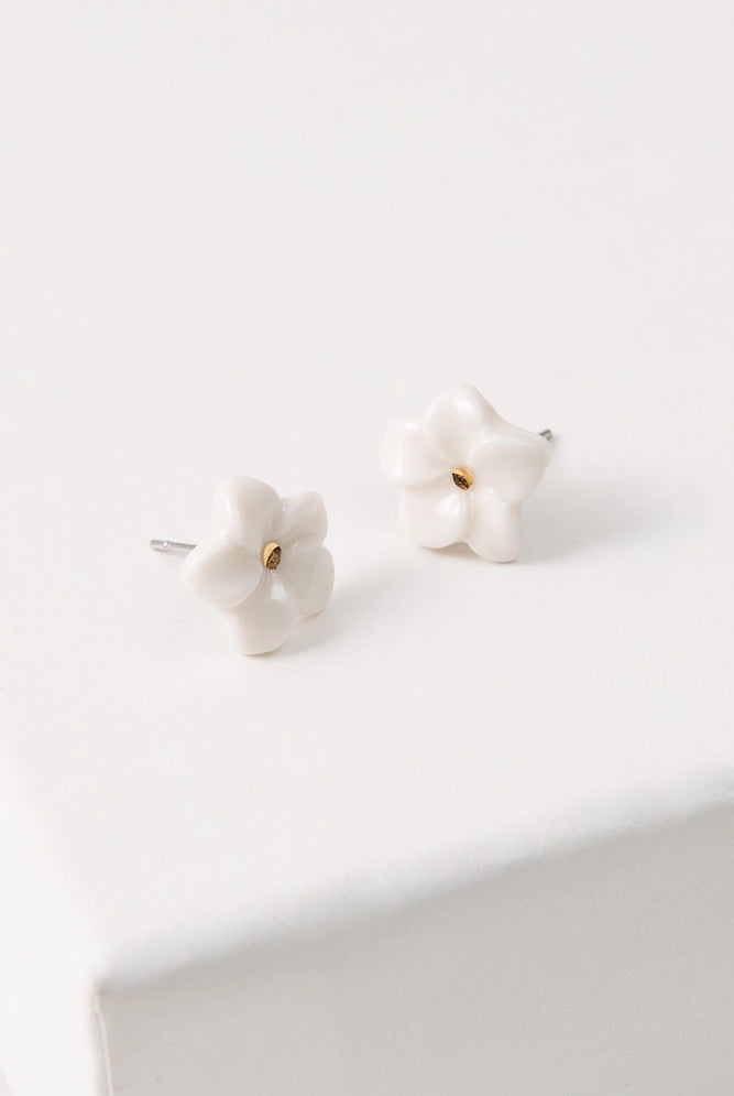 The Porcelain Plumeria Studs are small flower-shaped studs composed of white porcelain. At the center of the flowers is a dot of shining gold luster.