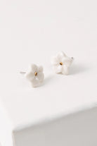 The Porcelain Plumeria Studs are small flower-shaped studs composed of white porcelain. At the center of the flowers is a dot of shining gold luster.