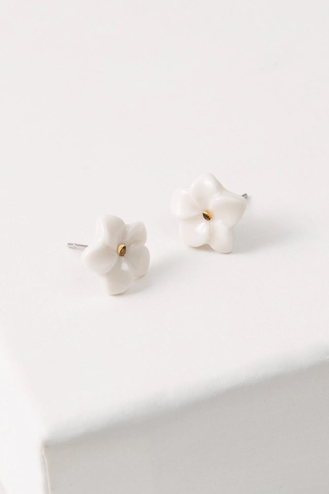 The Porcelain Plumeria Studs are small flower-shaped studs composed of white porcelain. At the center of the flowers is a dot of shining gold luster.