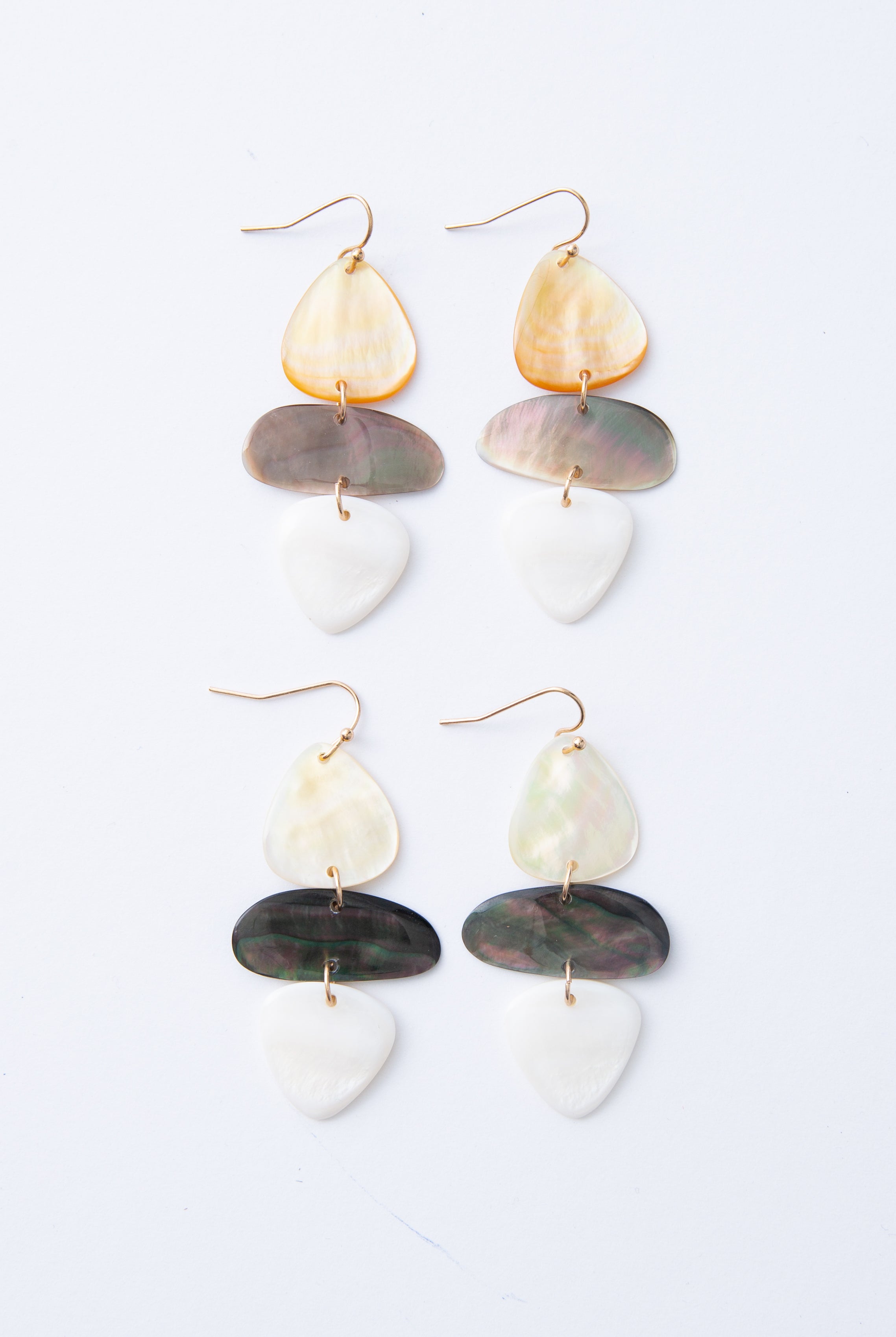 Two pairs of Shell Stack Earrings are shown together, demonstrating the natural variations in color that can occur between pairs. The shell pieces can be either lighter or darker due to the natural shell material.
