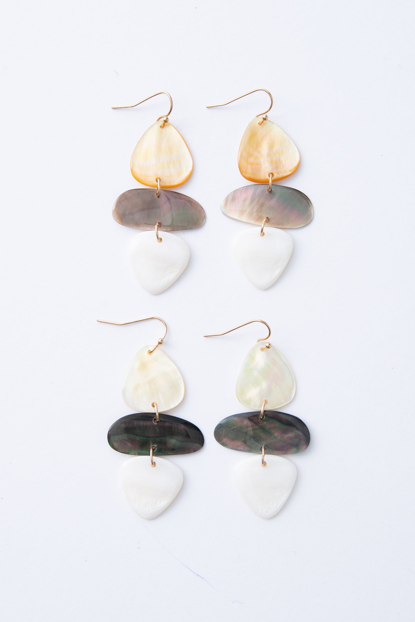 Two pairs of Shell Stack Earrings are shown together, demonstrating the natural variations in color that can occur between pairs. The shell pieces can be either lighter or darker due to the natural shell material.