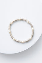 This is a single-strand bracelet composed of hundreds of sequin-like silver discs made of shining metal. Every inch or so, there is a round glass pearl strung between the metal sequins.