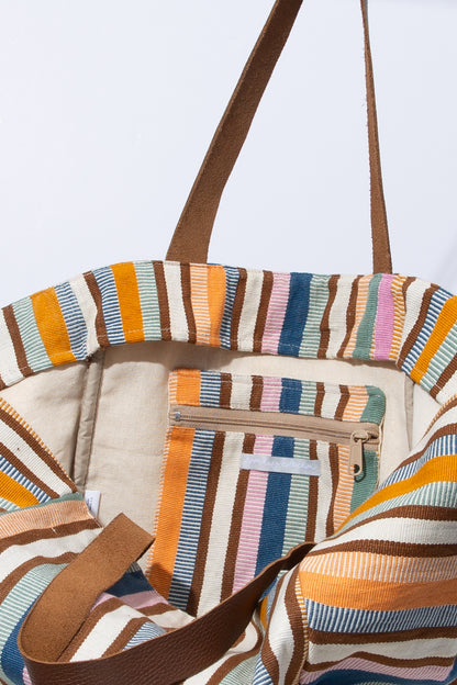 The interior of the Sunkissed Tote is shown. It has a cream cotton lining. There is an interior zipper pocket made of the bag's striped fabric stitched into the wall of the bag. 