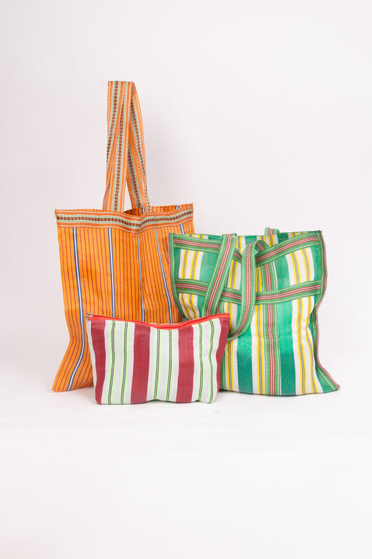   	 The three bags included in the Grab and Go Market Set sit together. Two of the bags are identical in size, and are large, square totes with shoulder straps. The third bag is a smaller zipper pouch that is wider than it is tall. All three bags are made of upcycled nylon with a stripe pattern, but the colors vary on each.