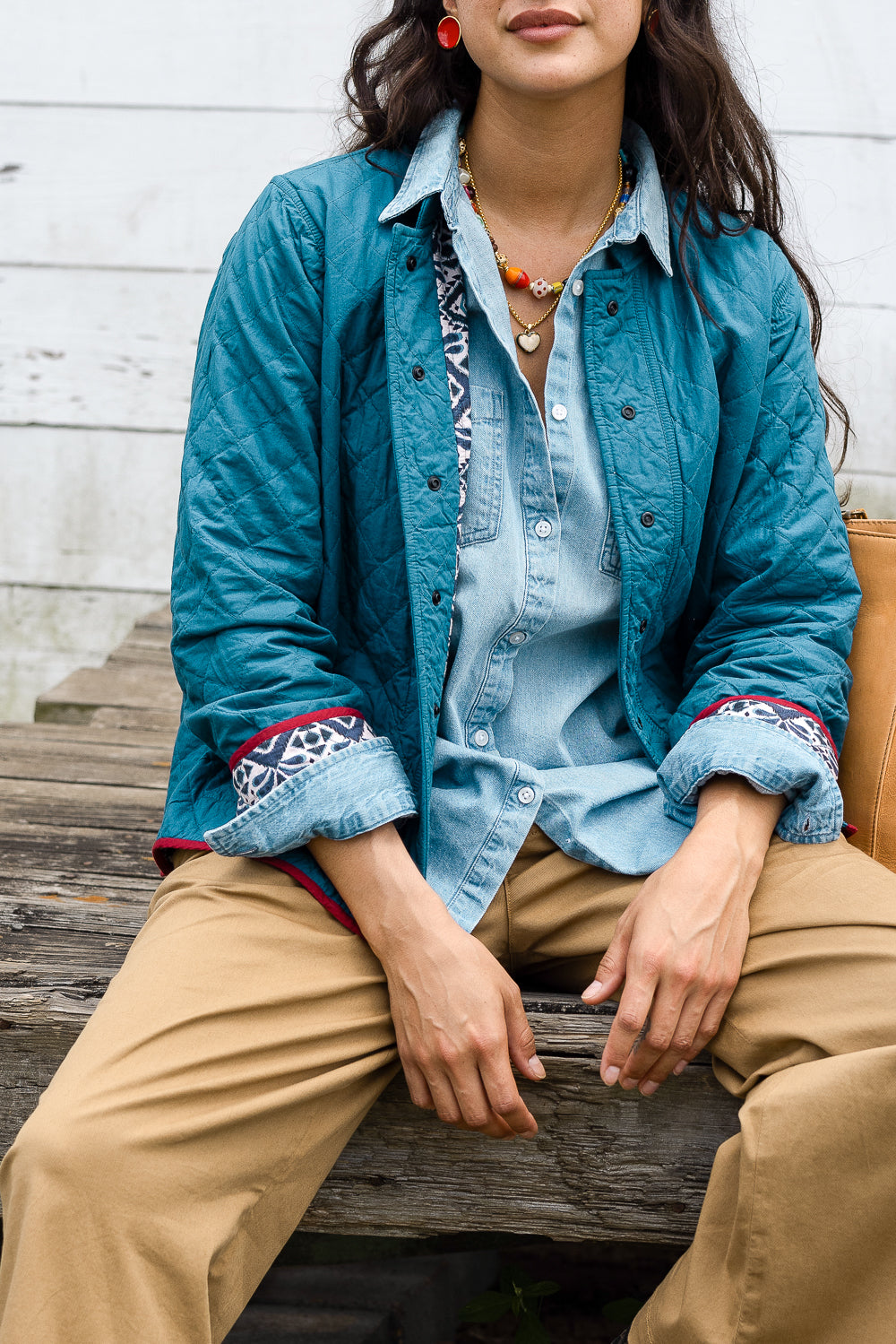 The jacket is shown with its print fabric worn on the interior. The exterior is solid teal fabric. Pop of the navy and white print adorn the jacket's cuffs. 