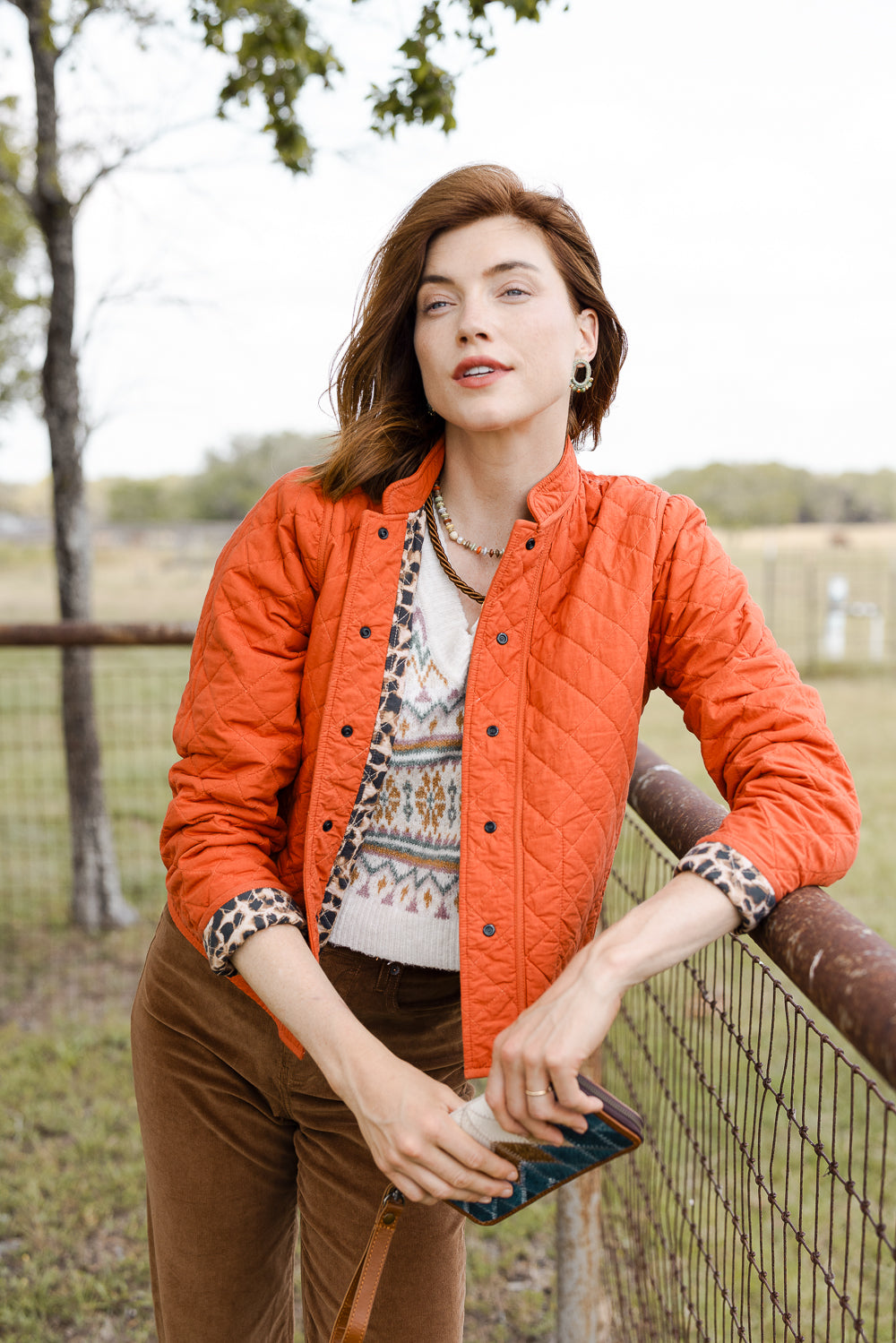 The jacket is shown with its leopard print fabric worn on the interior. The exterior is solid bright orange fabric. Pops of leopard print adorn the jacket's cuffs. 