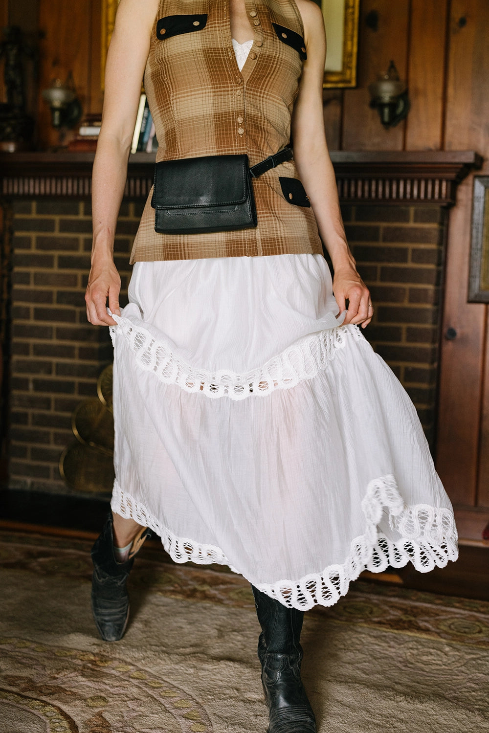 The bag is shown being worn as a belt bag or fanny pack. The long black leather strap wraps around the model's waist, and the small bag sits at the front.