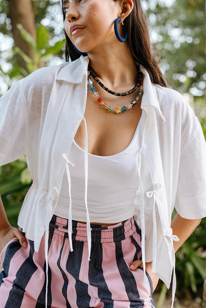 The Tie Cinch Blouse is worn untied over a white tank top.