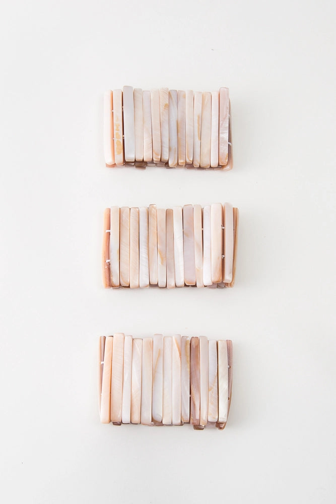 Three Beachcomber Bracelets are pictured. Due to the natural shell used, each varies slightly in shade. However, all have peach and white tones.