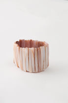 The Beachcomber Bracelet is composed of many tall strips of shell strung along elastic. The shell pieces vary in color, but each has peach and white tones.