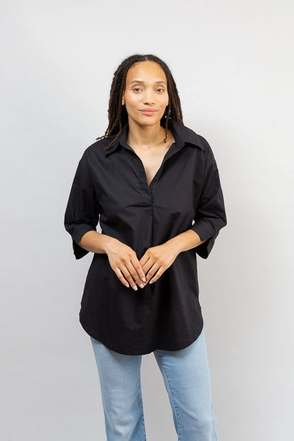 A model wears the Black Breezy Tunic untucked. It hits a few inches below her hips. 