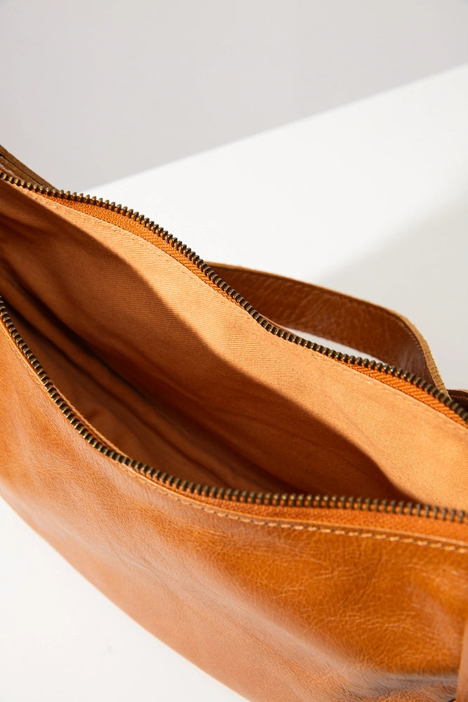 The interior of the Crescent Sling Bag is lined with caramel-colored cotton fabric. It contains no interior pockets.