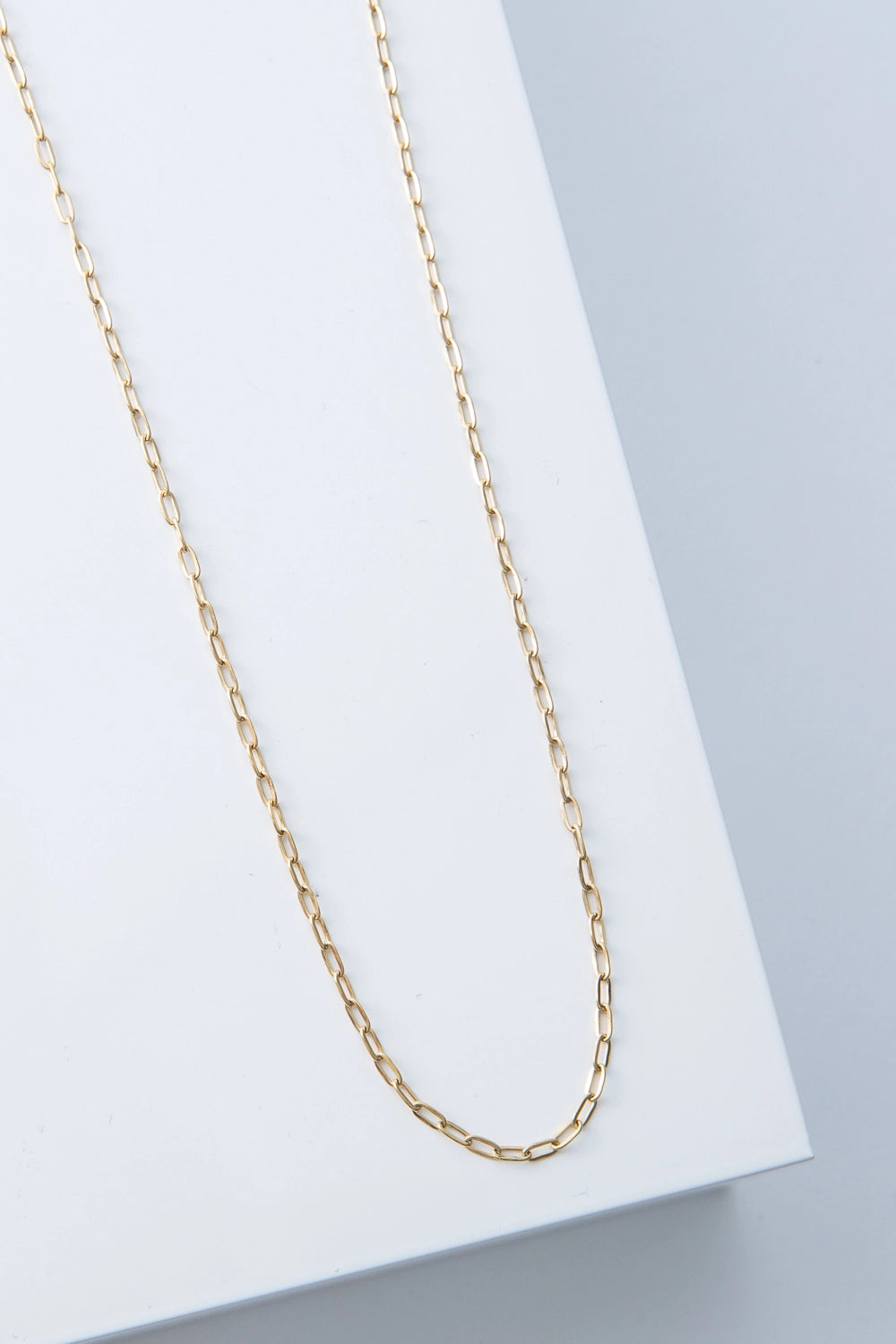 This is a single-strand gold chain necklace. The gold metal has a shiny finish, and the links are a flattened oval shape. 