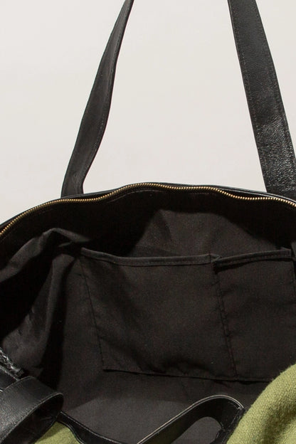 The interior of the bag is pictured. The bag has a black fabric lining and two fabric slot pockets stitched into the front wall of the bag.