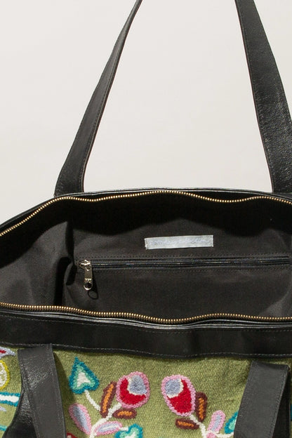 The interior of the bag is pictured. The bag has a black fabric lining and has a zipper pocket stitched into the back wall of the bag.