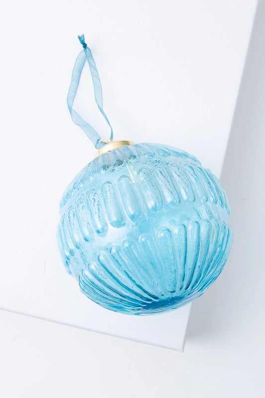 The Gatsby Globe Ornament is a spherical ornament composed of transparent light blue glass. The glass is accented with a geometric pattern of lines that wrap around the sphere for an art deco-inspired look. The ornament is finished with a brass top and blue ribbon.