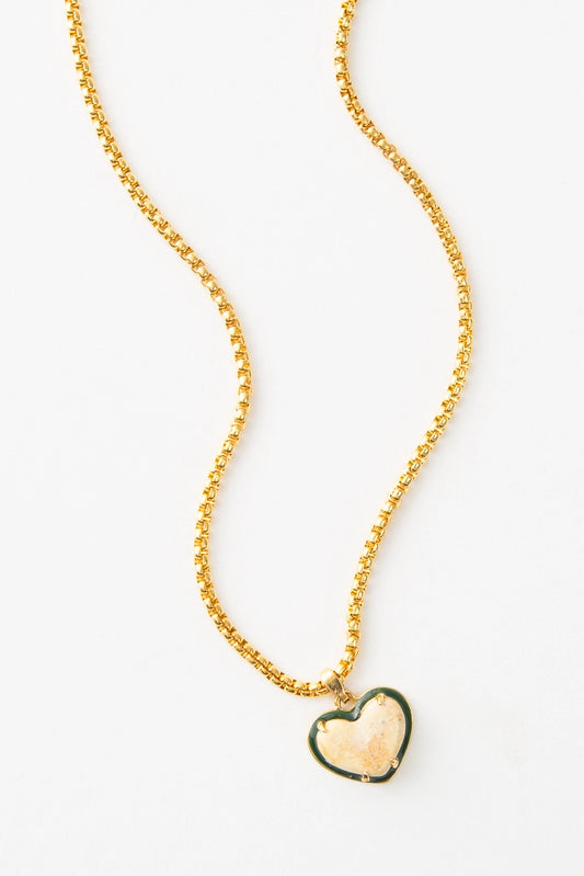 The Heart of Marble Necklace has a dainty gold chain and a small, heart-shaped pendant. The pendant is composed of peach colored marble that is outlined in black.