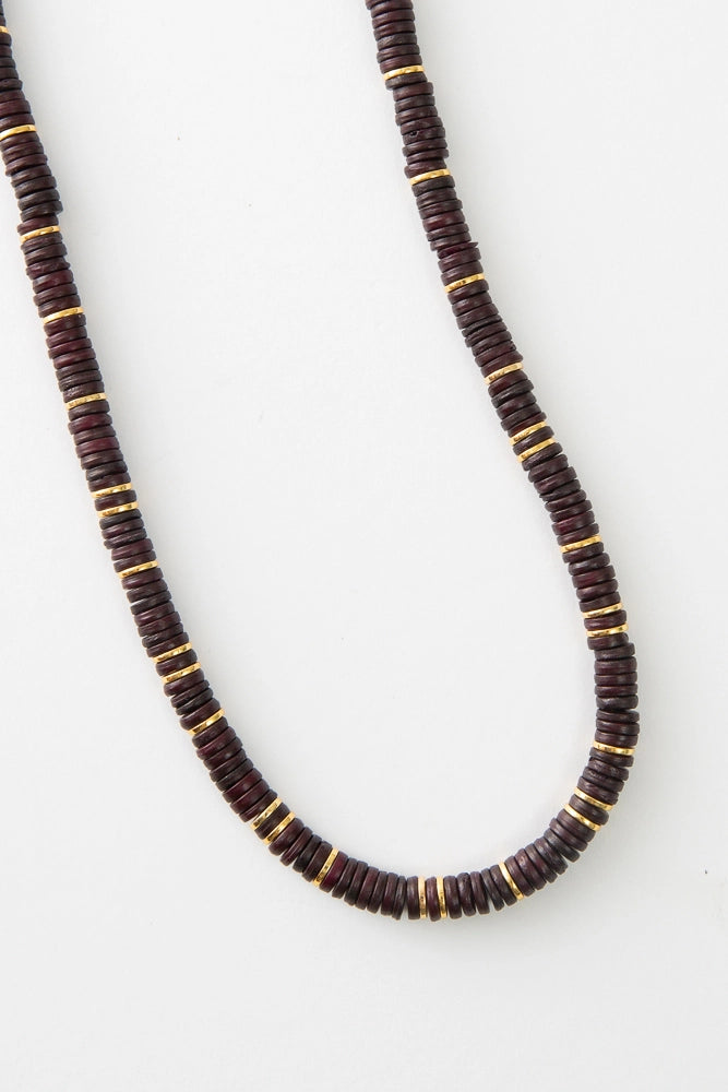 The Heishi Necklace is composed of hundreds of dark brown discs strung all along the necklace. Every inch or so, the necklace is accented with shining brass discs that alternate with the brown horn discs.