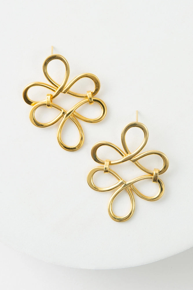 The Infinity Loop Earrings are large chandelier-style earrings. They are composed of a brass bar that is twisted around to form six loops that circle around the center of the earring. 