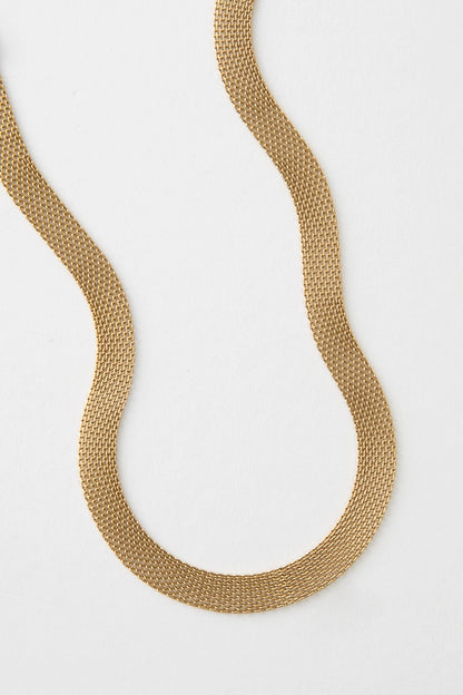 The Interwoven Necklace is a short, ribbon-style necklace composed entirely of gold plated metal links. The tiny links form a broad, flat chain. 