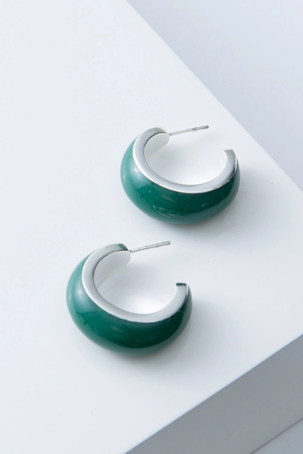 These are demi-hoop earrings that are open at the back. The hoops have a silver plated bronze base that is coated in a thick, smooth layer of rich green enamel. The earrings have a steel post.