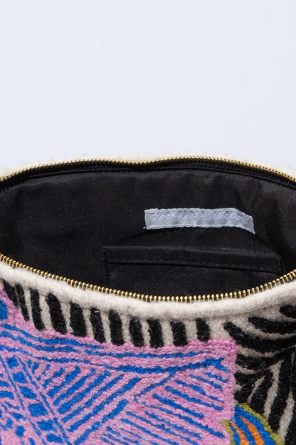 The Macaw Crossbody is shown unzipped. The interior is lined with black fabric. There is an interior pocket stitched into the back wall of the bag. 