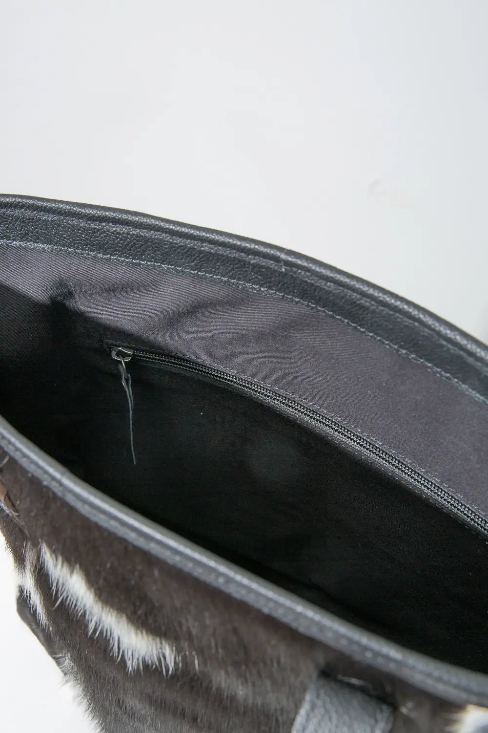 The interior of the Modern Leather Cowhide Tote is shown. There is an interior zipper pocket stitched into one wall of the bag.