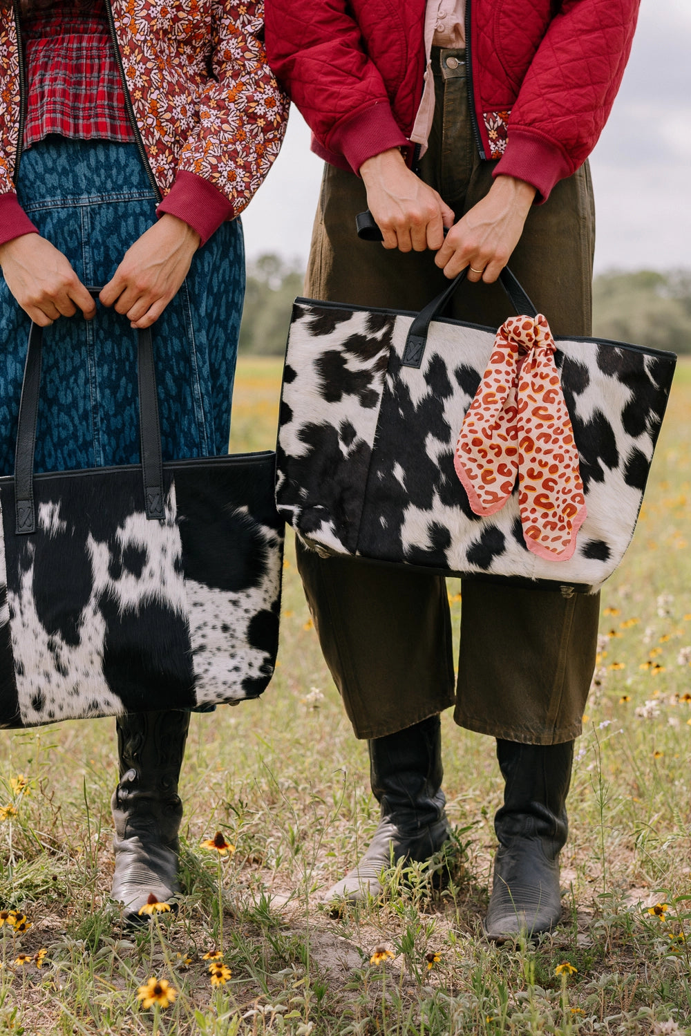 Two totes are shown side by side, demonstrating the different cowhide patterns that can occur due to the natural materials used to craft the bag.