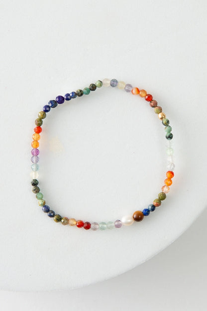 The Refraction Bracelet is a single stranded beaded bracelet. It is composed of tiny faceted crystal, semi-precious stone, brass, and pearl beads. The beads are many different bright shades, giving the bracelet a rainbow look.