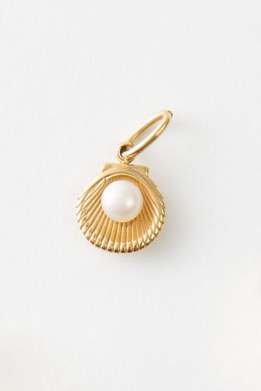 The Seek Charm is an open gold metal shell charm with a pearl in the center. It hangs from a gold ring.