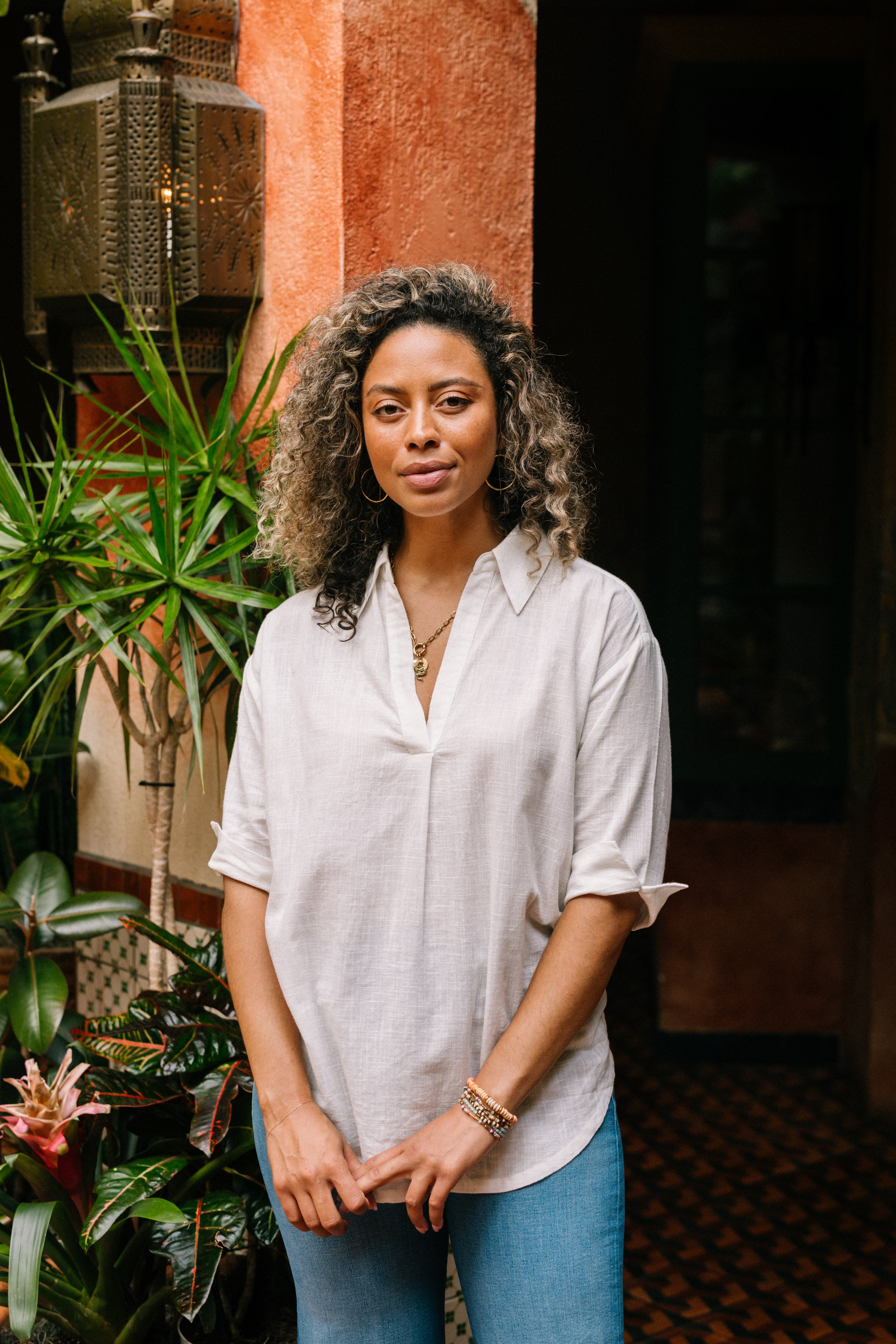 The White Breezy Tunic is a simple white cotton blouse with an easy, flowy silhouette. It has elbow-length sleeves and a v-neck with a collar. The tunic hits below the hips. 